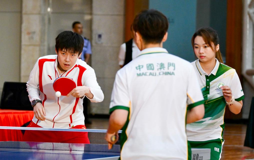 9月1日，乒乓球運動員王楚欽（左）與澳門運動員切磋球技。當日，內地奧運健兒代表團在澳門奧林匹克體育中心室內體育館與澳門青少年運動員進行互動交流。新華社記者 郭雨祺 攝