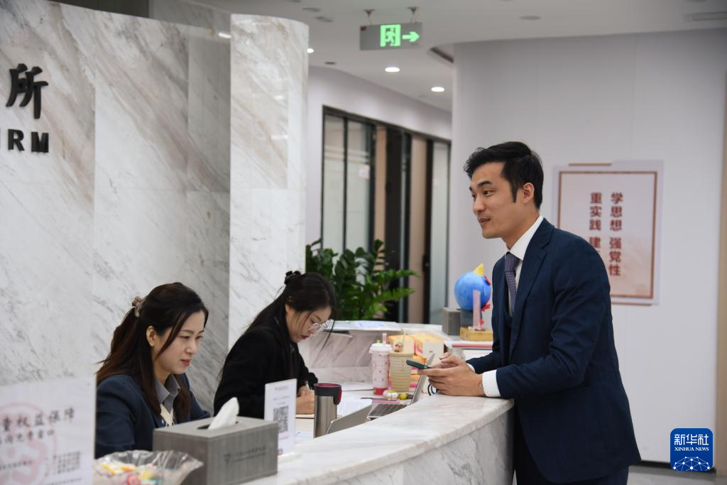 澳門律師阮嘉銳（右）在和同事交談（12月19日攝）。新華社記者 洪澤華 攝