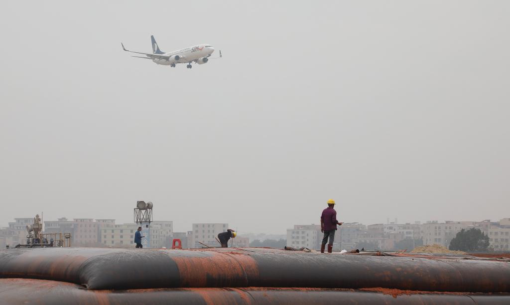 2025年1月23日，一架準備降落的飛機經過白云機場擴建工程施工現場。新華社記者 田建川 攝
