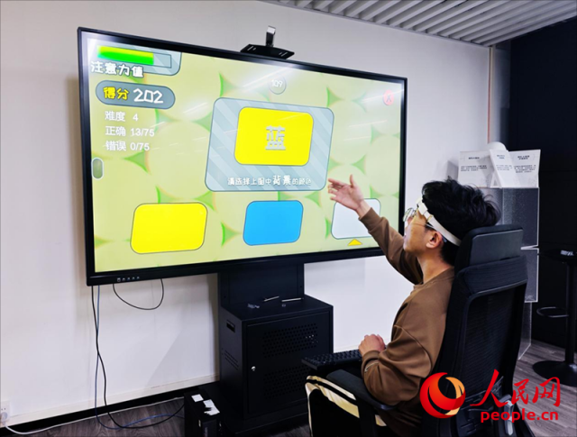 廣州琶洲實驗室工作人員演示腦機接口設備如何操作專注力訓練游戲。人民網 樸馨語攝