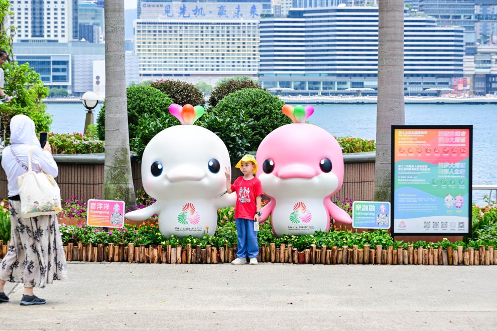 圖為一名兒童在香港金紫荊廣場(chǎng)的第十五屆全國運(yùn)動(dòng)會(huì)吉祥物旁留影