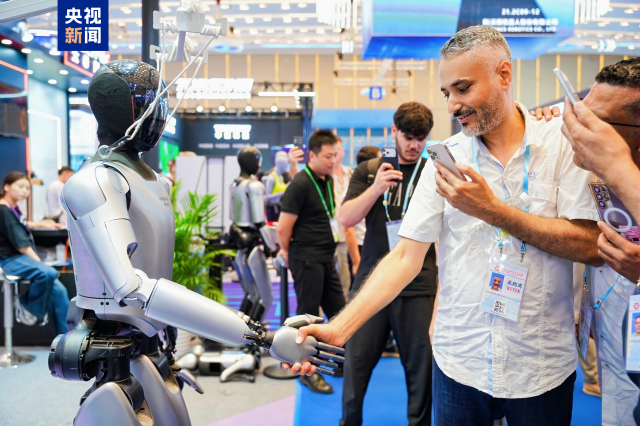 廣交會現場，參會人員正與機器人握手互動。