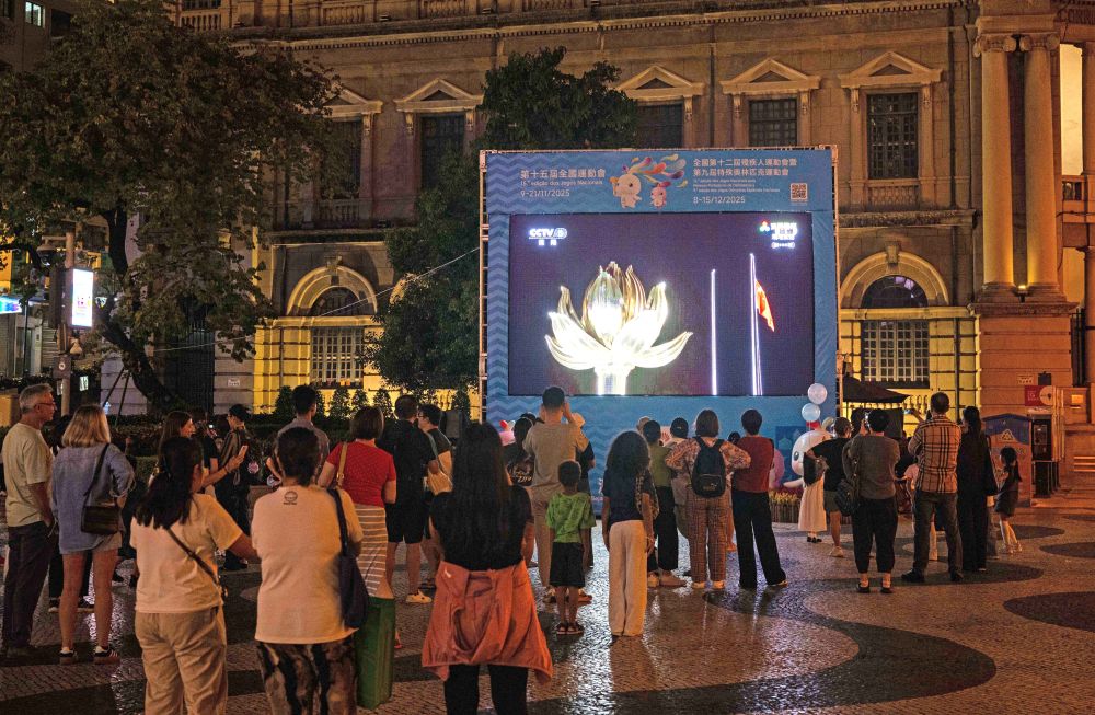 11月9日，第十五屆全國運動會開幕式在廣東奧林匹克體育中心舉行，這是群眾在澳門街頭觀看直播。新華社發（張金加 攝）