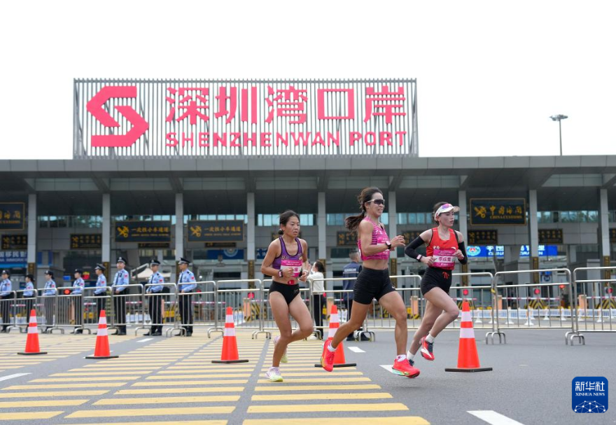 十五運(yùn)會(huì)馬拉松項(xiàng)目是全運(yùn)會(huì)歷史上首場跨境馬拉松賽事，運(yùn)動(dòng)員從起跑到完賽，其生物特征與實(shí)時(shí)位置數(shù)據(jù)已與后臺(tái)系統(tǒng)同步融合，比賽參賽選手無需改變自己的節(jié)奏，在奔跑中便完成了跨境通關(guān)。圖為十五運(yùn)會(huì)女子馬拉松比賽參賽選手經(jīng)過深圳灣口岸。
