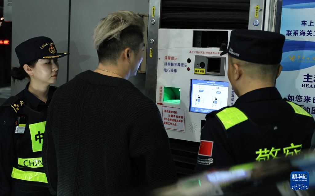 12月23日，“粵車南下”入境香港市區的首位通關車主彭先生（中）在“一站式”通道辦理通關手續。新華社記者 黃國保 攝