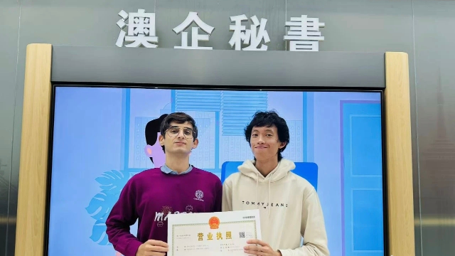 澳門青年陳葦楠與意大利伙伴馬丁在橫琴粵澳深度合作區政務服務中心的“澳企秘書”專窗前并肩而立