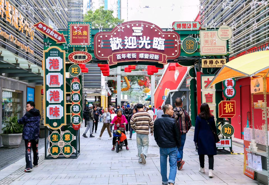 憑借毗鄰香港的獨(dú)特區(qū)位，大灣區(qū)內(nèi)地城市正將港式生活美學(xué)與跨境消費(fèi)體驗(yàn)深度融入城市肌理，打造“港風(fēng)港味”的文旅消費(fèi)新場(chǎng)景。在沙頭角港式風(fēng)情街區(qū)，建筑風(fēng)貌、商鋪招牌、街頭視覺(jué)與聽覺(jué)元素高度還原了經(jīng)典港式街區(qū)氛圍，匯聚國(guó)際美妝、潮流服飾、港式茶餐廳、跨境商品等特色商戶，并融入魚燈舞等非遺元素，滿足了消費(fèi)者對(duì)港式風(fēng)情與跨境購(gòu)物的一站式體驗(yàn)需求，是深港融合文化在消費(fèi)領(lǐng)域的生動(dòng)體現(xiàn)，成為網(wǎng)紅打卡與消費(fèi)熱點(diǎn)。